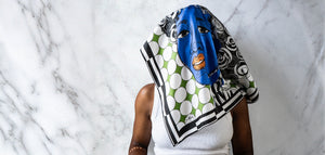 Person wearing a colorful scarf with a blue mask over their face against a marble background